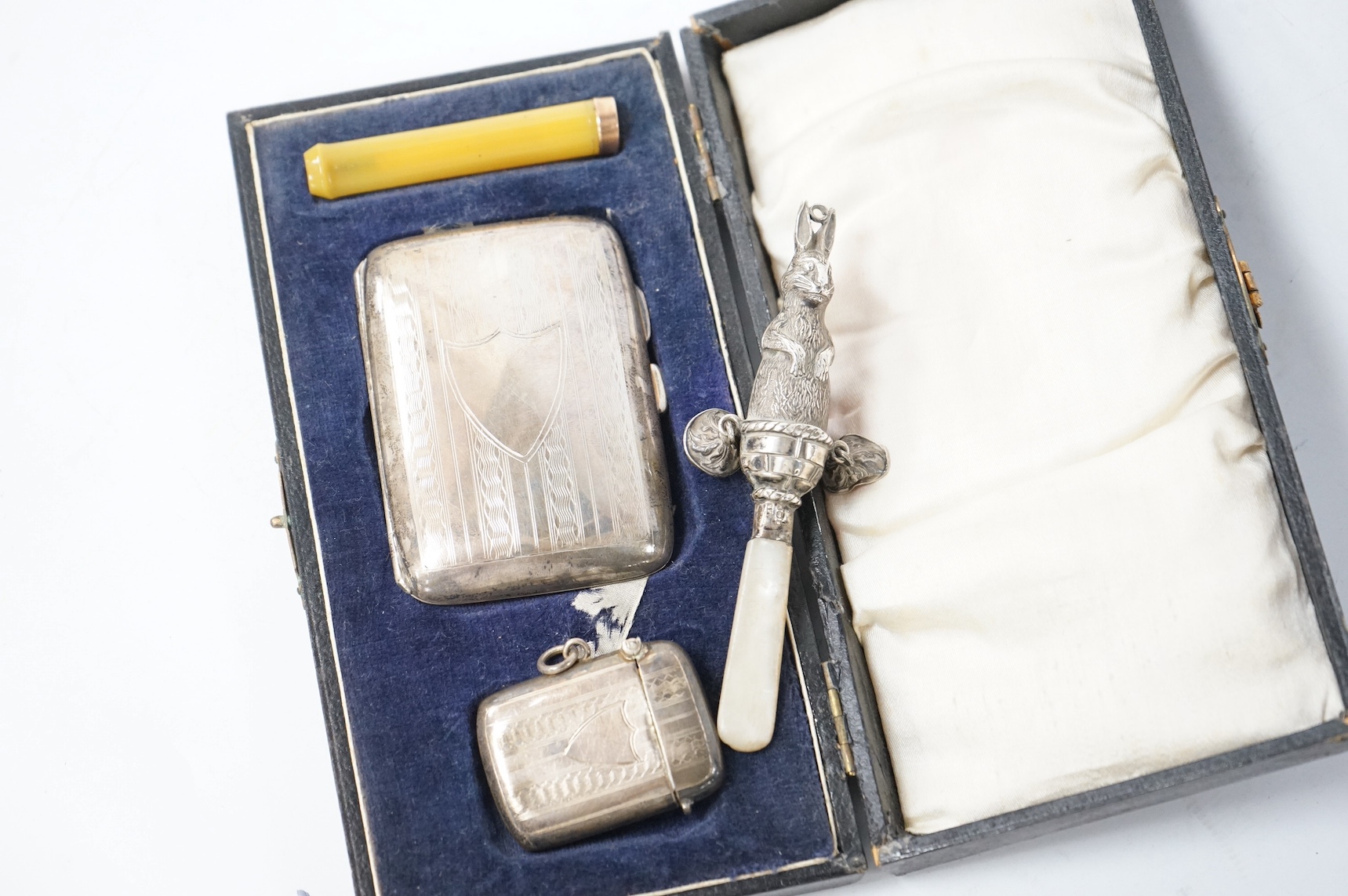 A cased George V three piece smoker's set, comprising a silver cigarette case and vesta case, F.D. Long, Birmingham, 1922 and an associated? 9ct mounted amberoid cigarette holder, together with a George V silver and moth